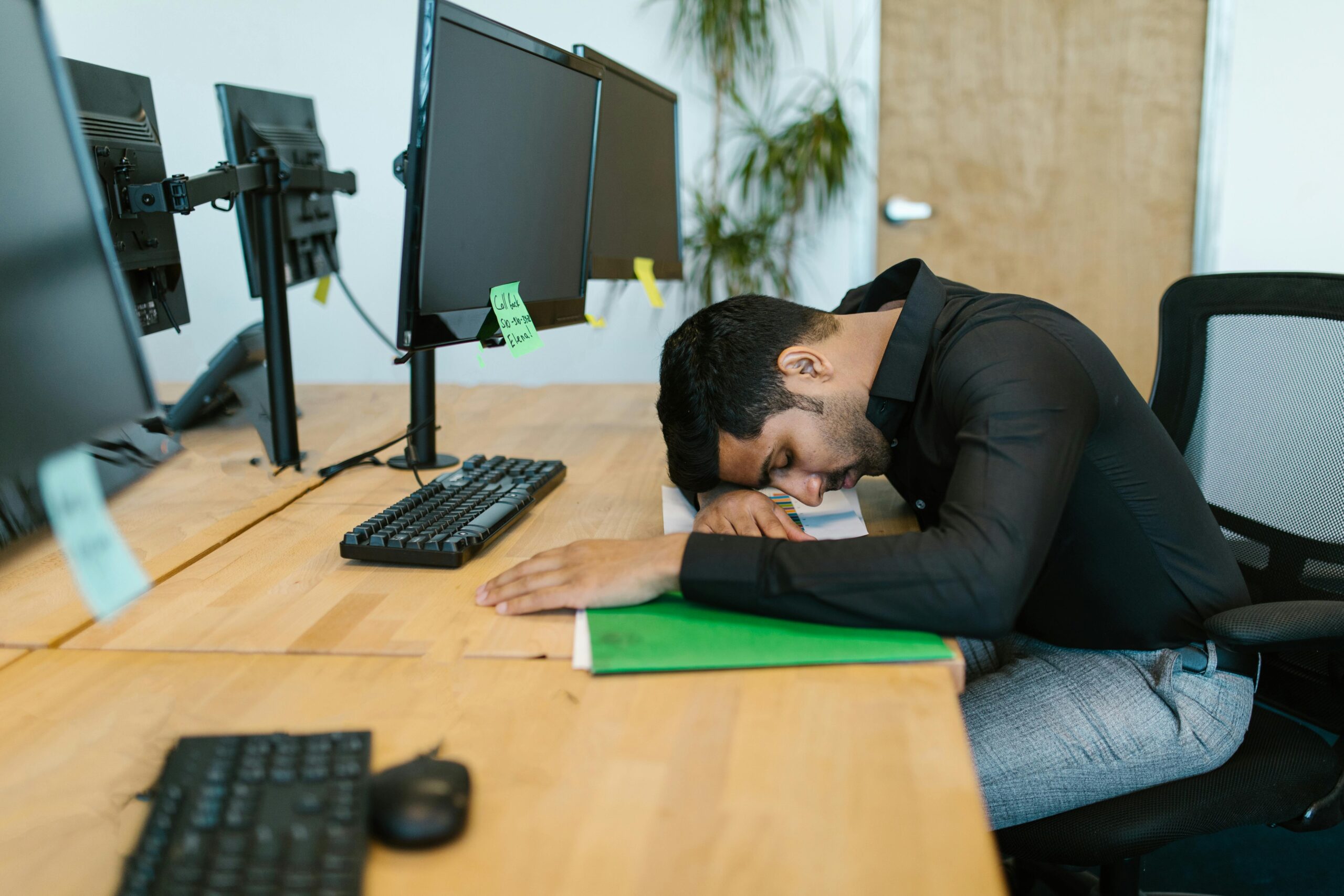 a tired indian man sleeping on office desk